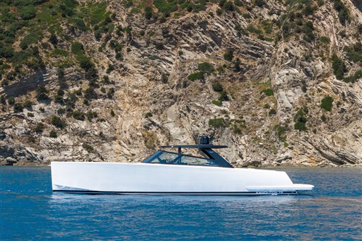 2025 VanDutch 75 yacht cruising near rocky coastline, showcasing sleek design and luxury.