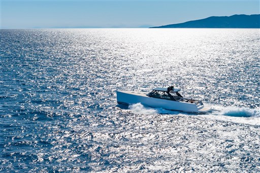 2025 VanDutch 75 yacht cruising on sparkling blue ocean with distant island view.
