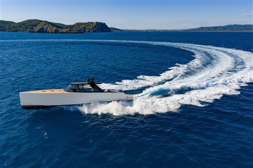 2025 VanDutch 75 yacht cruising swiftly on open blue sea with scenic island backdrop.