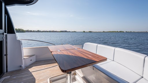 2024 Apreamare GOZZO 38 CABIN yacht deck with seating and table, overlooking serene water.