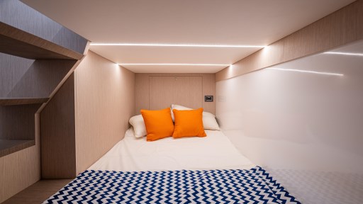 2024 Apreamare GOZZO 38 CABIN interior with cozy bed, orange pillows, and modern lighting.