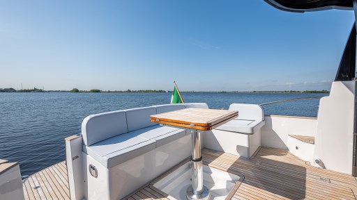 2024 Apreamare GOZZO 38 CABIN yacht deck with seating and table, overlooking serene water.