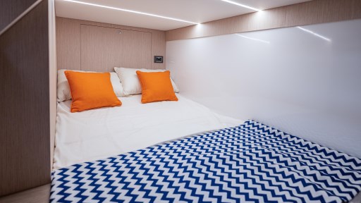 2024 Apreamare GOZZO 38 CABIN interior with cozy bed, orange pillows, and zigzag blanket.