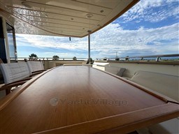Luxurious deck of 2008 Riva 115 Athena yacht with wooden table and scenic view.