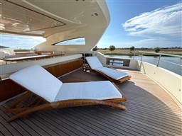 Luxurious deck of 2008 Riva 115 Athena yacht with sun loungers and scenic water view.