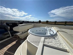 Luxurious 2008 Riva 115 Athena yacht deck with jacuzzi and seating under clear blue sky.