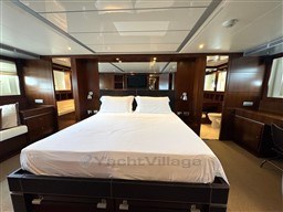 Luxurious bedroom interior on 2008 Riva 115 Athena yacht, featuring elegant wood paneling.