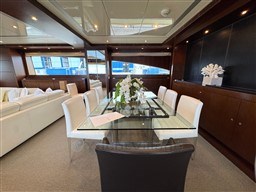 Luxurious dining area on 2008 Riva 115 Athena yacht with elegant glass table.