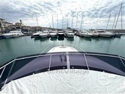 Prestige 590 yacht in marina, surrounded by boats, under cloudy sky, 2019 model.
