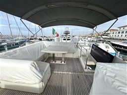 Flybridge of 2019 Prestige 590 yacht with covered seating, table, and marina view.