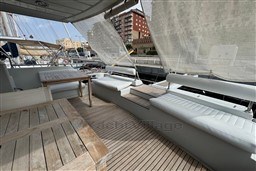 1989 Mochi Craft MOCHI 56 yacht deck with wooden seating and table, docked at marina.