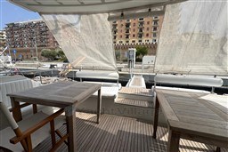 1989 Mochi Craft MOCHI 56 yacht deck with wooden tables and urban backdrop.