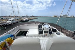 1989 Mochi Craft MOCHI 56 yacht cockpit with marina view, featuring steering controls and seating.