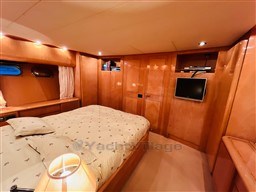 Luxurious bedroom interior of 1996 Sanlorenzo 62 yacht with wood paneling and modern amenities.