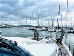 Sanlorenzo 62 yacht from 1996 docked in a marina with sailboats and cloudy sky.