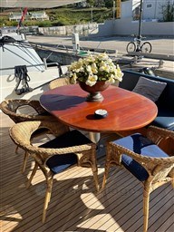 Outdoor dining area on a 1996 Sanlorenzo 62 yacht with wicker chairs and floral centerpiece.