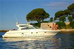 2005 Jeanneau Prestige 34 S yacht cruising near a scenic shoreline with trees.