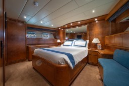Luxurious bedroom interior on 1999 Mangusta 105 Sport yacht, featuring elegant wood finishes.
