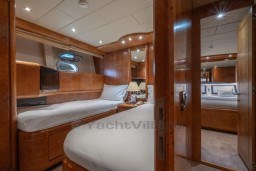 Luxurious 1999 Mangusta 105 Sport yacht cabin with elegant wood finishes and cozy beds.