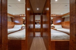 Luxurious interior of 1999 Mangusta 105 Sport yacht with twin beds and wooden finish.