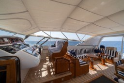 Luxurious 1999 Mangusta 105 Sport yacht interior with striped seating and ocean view.