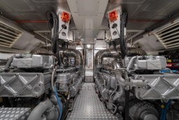 Engine room of a 1999 Mangusta 105 Sport yacht, showcasing dual engines and metallic components.