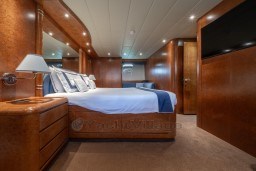 Luxurious bedroom interior of 1999 Mangusta 105 Sport yacht with elegant wood finishes.