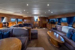 Luxurious interior of a 1999 Mangusta 105 Sport yacht with elegant seating and wooden accents.