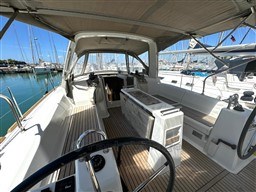Beneteau Oceanis 38.1 yacht cockpit, 2021 model, docked in a marina under clear blue skies.