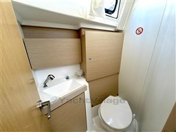 2021 Beneteau Oceanis 38.1 bathroom with modern sink, toilet, and wooden cabinetry.