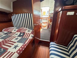 Interior of 2001 Beneteau Oceanis 40 CC with striped upholstery and American flag quilt.