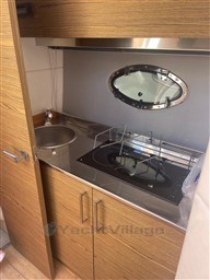 Compact kitchen area in 2013 Rio Yachts Rio 36, featuring stove, sink, and porthole window.