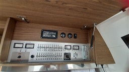 Control panel of 2013 Rio Yachts Rio 36, featuring gauges and switches in a wooden cabinet.
