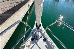 Bow of 2024 Dufour 37 yacht docked, with stainless steel railings and calm water.
