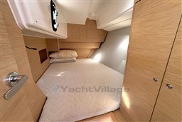 2024 Dufour 37 yacht cabin with cozy bed and wooden interior design.