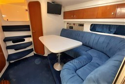 2002 Cranchi Smeraldo 37 yacht interior with blue seating, table, and wall-mounted TV.