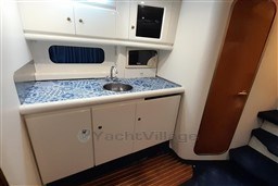 2002 Cranchi Smeraldo 37 yacht kitchen with blue patterned countertop and white cabinets.