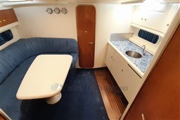 2002 Cranchi Smeraldo 37 yacht interior with blue seating, table, and kitchenette.