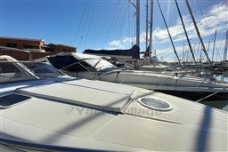 2002 Cranchi Smeraldo 37 yacht docked in a sunny marina, surrounded by sailboats.