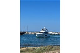 Azimut 68 Fly 2022 yacht in a serene marina setting under clear blue skies.