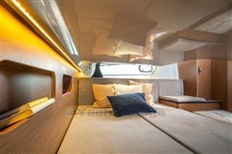 Luxurious interior of 2023 Beneteau Antares 11 with cozy bedding and ambient lighting.