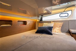 Luxurious interior of 2023 Beneteau Antares 11 with cozy bedding and ambient lighting.