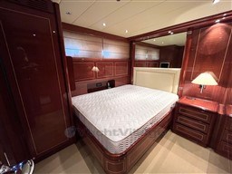 Luxurious bedroom interior of 2005 Mangusta 72 Open yacht with elegant wood paneling.