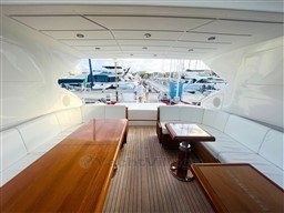 Luxurious 2005 Mangusta 72 Open yacht interior with elegant wood and white seating.