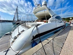 Luxury 2005 Mangusta 72 Open yacht docked at marina under blue sky.