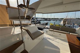 2024 Fountaine Pajot Isla 40 catamaran interior with marina view, featuring seating and wooden accents.