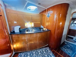 2005 Innovazione e Progetti Mira 43 yacht interior with wooden cabinetry and compact kitchen area.