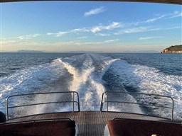 Wake of a 2002 Princess V65 yacht cruising on open sea under a clear sky.