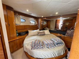 Luxurious cabin interior of 2002 Princess V65 yacht with cozy bed and elegant wood finish.
