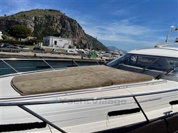 2002 Princess V65 yacht docked with scenic mountain backdrop and clear blue sky.